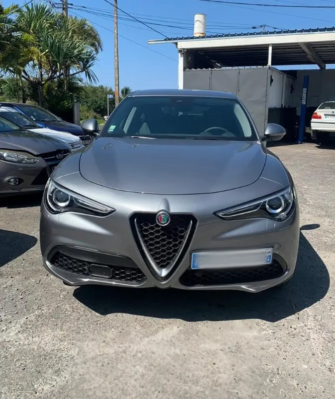 Alfa Romeo Stelvio stationnée devant le garage M.A.D Autos, enseigne visible