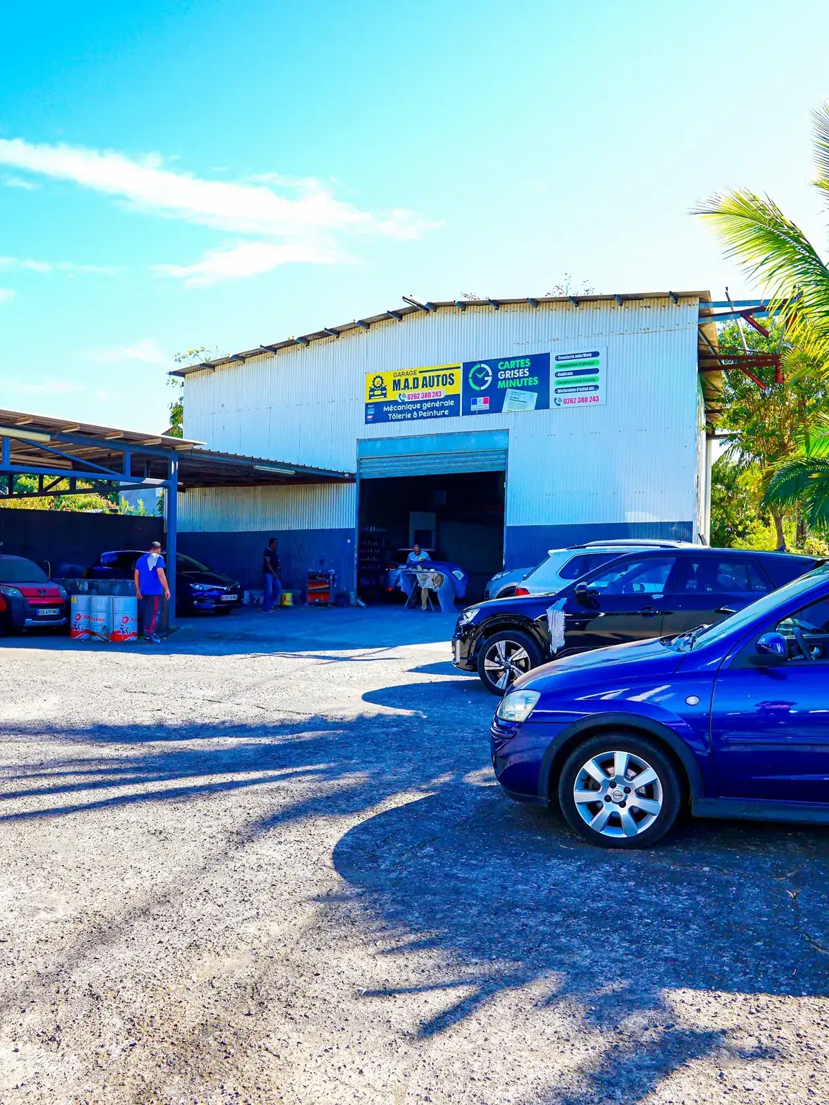 Le garage M.A.D Autos vu de l&rsquo;extérieur, véhicules stationnés devant l&rsquo;atelier